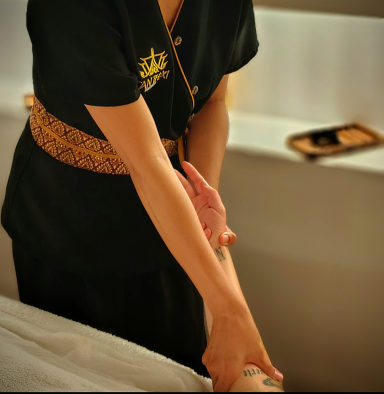 Masajista nativa tailandesa realizando técnica del masaje tradicional tailandés en el brazo